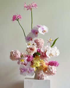 a white vase filled with lots of pink and yellow flowers