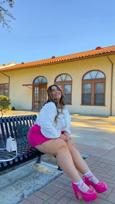 a woman sitting on a bench in front of a building with windows and pink shoes