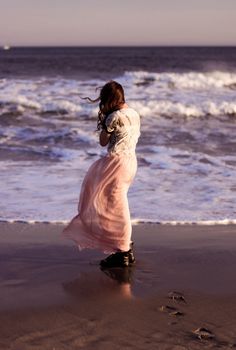 a woman standing on top of a beach next to the ocean