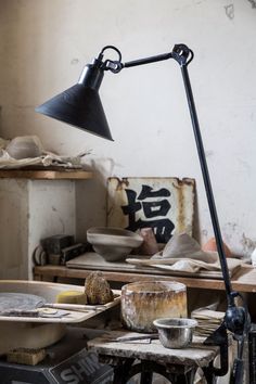 an old table lamp sitting on top of a wooden table next to bowls and pottery