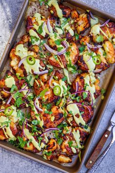 a pan filled with chicken and vegetables on top of a table next to utensils