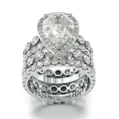 a wedding ring set with a pear shaped diamond center surrounded by round brilliant cut diamonds