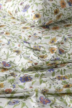 an image of a flowered sheet set on top of the bedding with white sheets