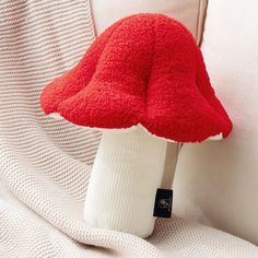 a red mushroom hat sitting on top of a white couch next to a white pillow