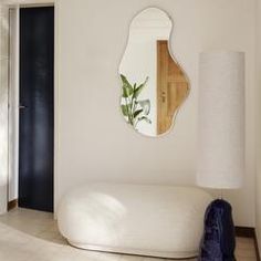 a white couch sitting under a mirror in a living room next to a wall mounted lamp