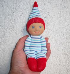 a hand holding a red and blue striped doll