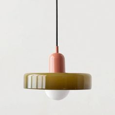 a pink and green light hanging from a ceiling fixture with a white wall in the background