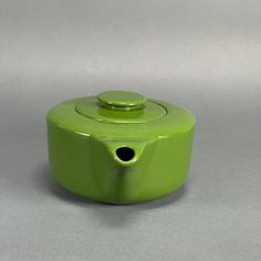 a green ceramic container with a hole in the center on a gray surface, it appears to be empty