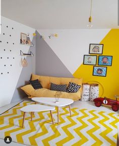 a living room with yellow and white decor on the walls, rugs and pictures on the wall