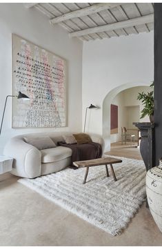 a living room with a white rug and large art piece on the wall above it