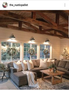 a living room with couches and christmas wreaths on the windows, lights hanging from the ceiling