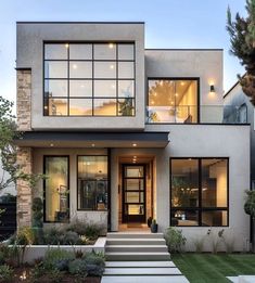 a modern house with large windows and steps leading up to the front door that lead into the yard