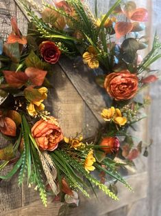 a wreath with orange and yellow flowers hanging on a wooden door frame in front of a window