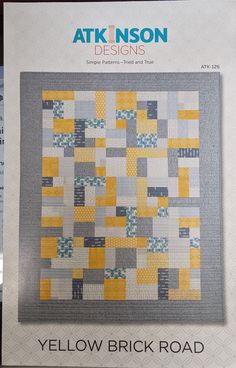 the front cover of a book with an image of a yellow and gray patchwork quilt