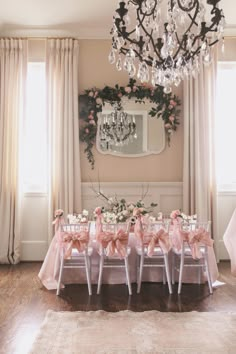 a dining room table with pink bows on it and chandelier hanging from the ceiling