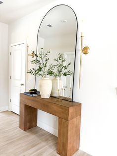 a mirror sitting on top of a wooden table next to a vase filled with flowers