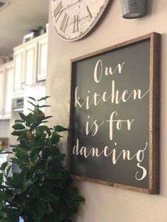 a kitchen is for dancing sign next to a potted plant and clock on the wall