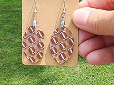 a pair of earrings with footballs on them is being held by a person's hand