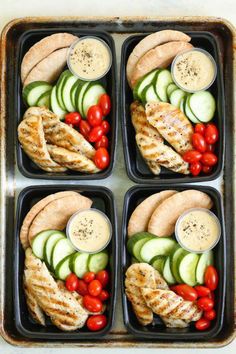 four trays filled with chicken, cucumbers and tomatoes on top of each other