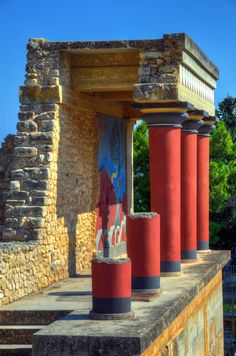 some red and blue pillars on the side of a building with trees in the background