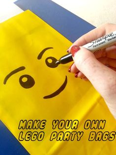 a hand holding a marker near a yellow bag with a smiley face drawn on it