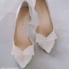 the bride's white shoes are adorned with pearls