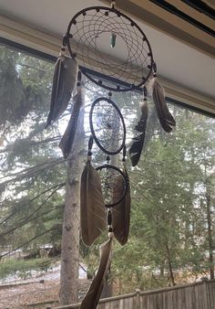 a dream catcher hanging from the side of a window in front of a tree and fence