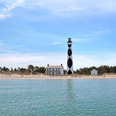 a black and white lighthouse sitting on top of a sandy beach