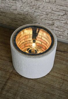 a fire pit sitting on top of a rug next to a brick wall and floor