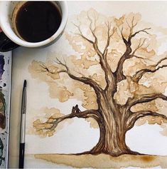 a cup of coffee sitting on top of a table next to a drawing of a tree