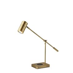 a gold desk lamp on a white background with a black dot below the light fixture