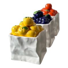 three white ceramic fruit containers filled with oranges, lemons, and blueberries