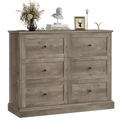 a large wooden dresser with drawers and flowers on top, against a white background that has an image of a busturine in the corner