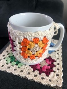 a crocheted coffee cup on top of a table next to a doily