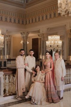 a group of people standing next to each other in front of a chandelier