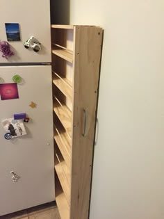 a white refrigerator freezer sitting inside of a kitchen next to a wooden shelf filled with magnets