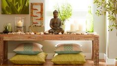 a buddha statue sitting on top of a wooden table in front of a window filled with candles