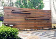 a large wooden fence is in the middle of a brick walkway with plants and bushes