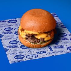 a cheeseburger sitting on top of a wrapper with blue paper around it