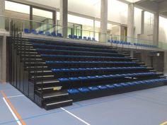 an empty bleachers with blue seats and railings in the middle of it