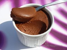 two scoops of chocolate ice cream in a small white bowl on a purple and white tablecloth