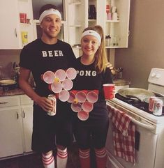 a man and woman standing next to each other in the kitchen with paper flowers on them