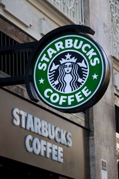 a starbucks sign hanging from the side of a building