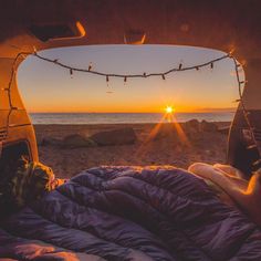 the sun is setting in front of an open camper