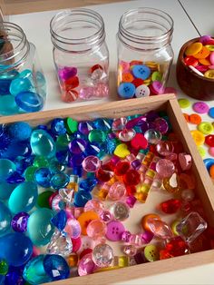 jars filled with colorful buttons sitting on top of a table