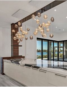 a modern kitchen with marble counter tops and hanging glass globe lights over the island area