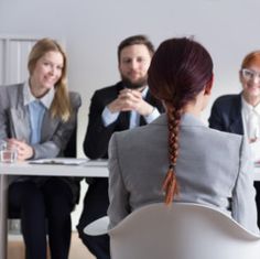 a group of people sitting at a table in front of a woman with red hair