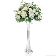 a clear vase filled with white flowers and greenery