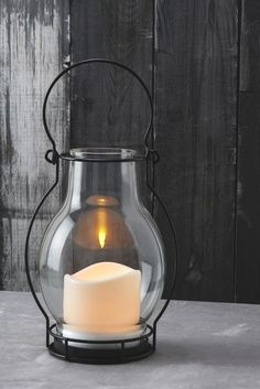 a lit candle in a glass jar on a table