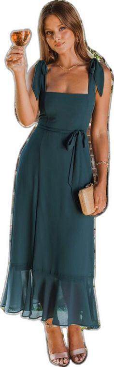 a woman in a green dress is holding a drink and a small purse with her right hand